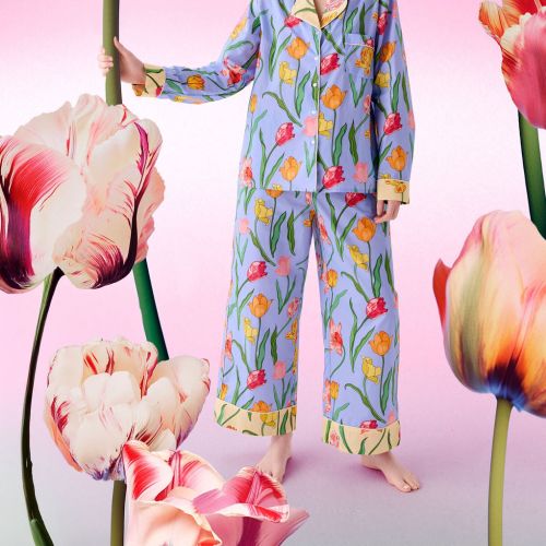 Woman in colorful floral pajamas with giant tulips on pink backdrop