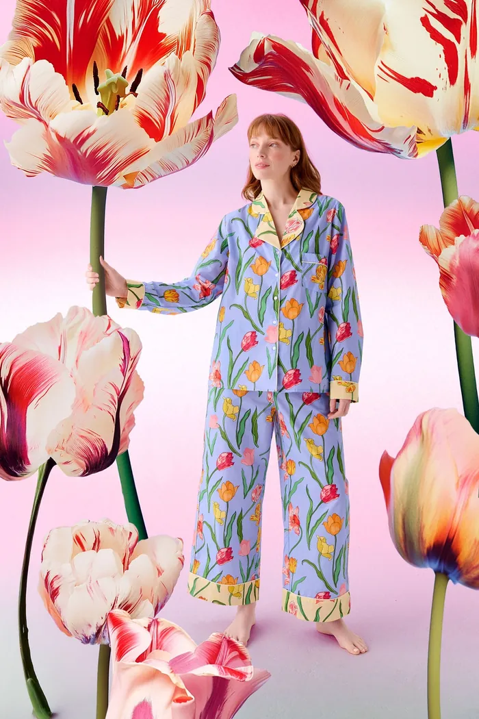 Woman in colorful floral pajamas with giant tulips on pink backdrop