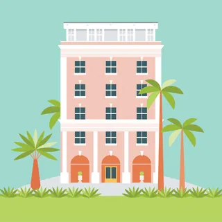 Pink hotel building with palm trees and grass under blue sky