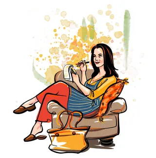 Woman writing in notebook while sitting on armchair with cushion