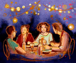 Four people enjoying a summer dinner party under string lights