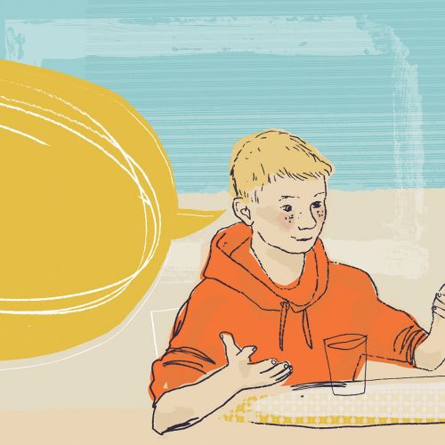Two boys talking and gesturing at a table indoors
