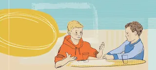 Two boys talking and gesturing at a table indoors