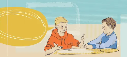 Two boys talking and gesturing at a table indoors