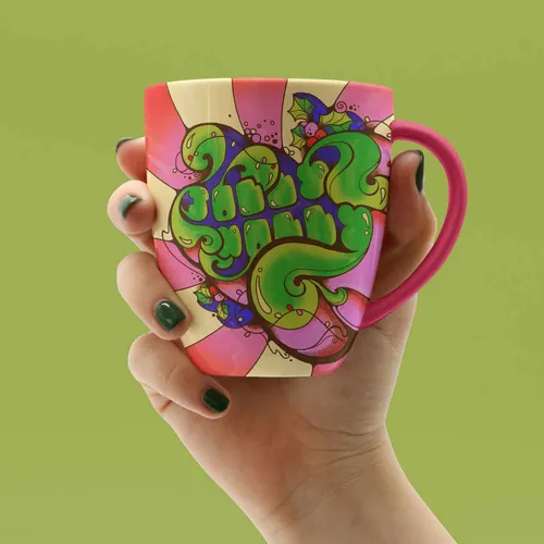 Hand holding colorful 1960s style mug with Jolly Holly design by Laura Greenan