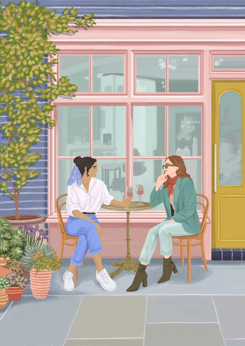 Two women drinking coffee and chatting at outdoor café seating