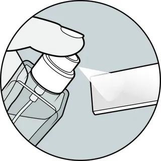 Hand spraying liquid from a spray bottle onto a surface