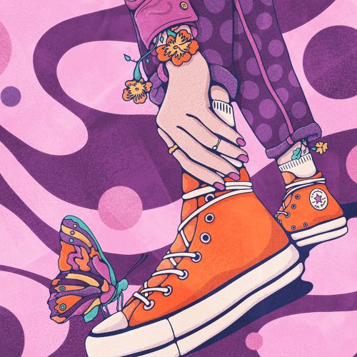 Hands holding orange sneakers with butterfly on shoe by Lively Scout