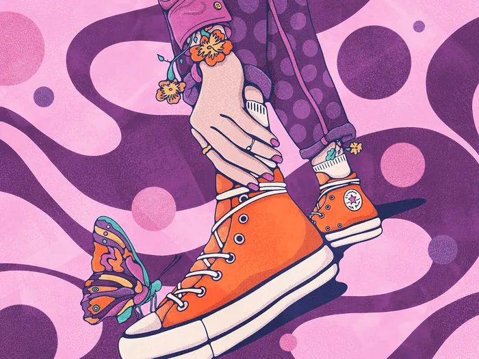 Hands holding orange sneakers with butterfly on shoe by Lively Scout