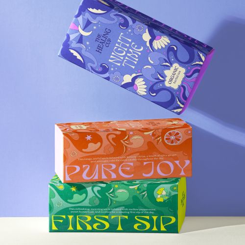 Stack of three vibrant tea boxes with decorative designs on purple surface