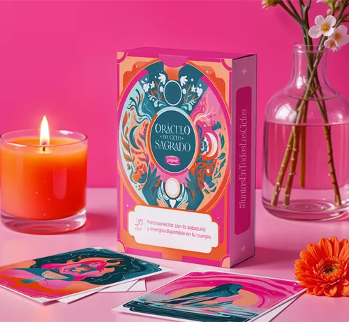 Liz Merino's Oráculo del Ciclo Sagrado card deck with candle and flowers