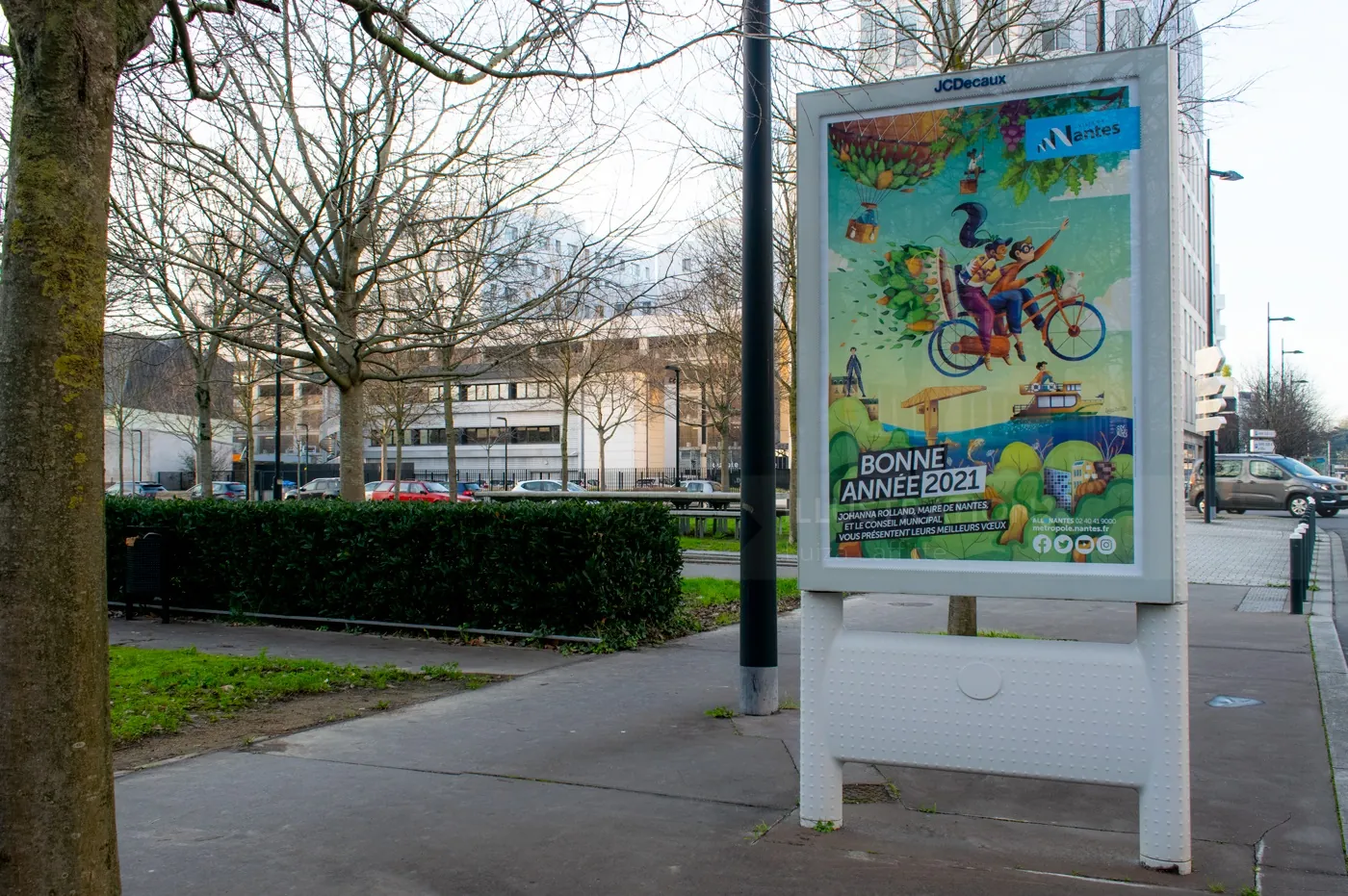Street billboard showing colorful nature-themed ad with cyclist and animals by Luiza Laffitte