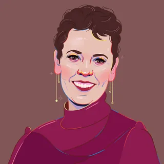 Smiling person with short curly hair wearing purple turtleneck and earrings