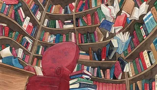 Red armchair in front of curved bookshelves full of books by Manu Cunhas
