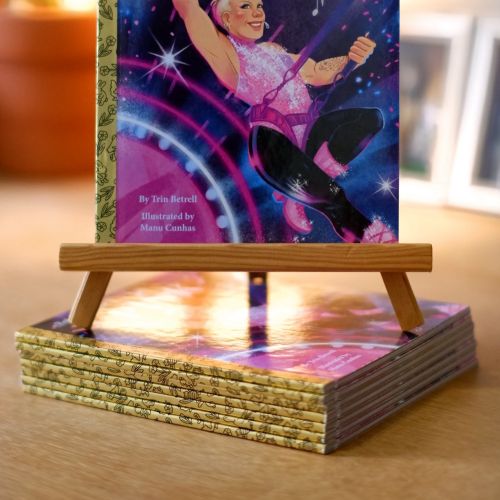 Manu Cunhas illustration of a Pink biography book on a wooden easel