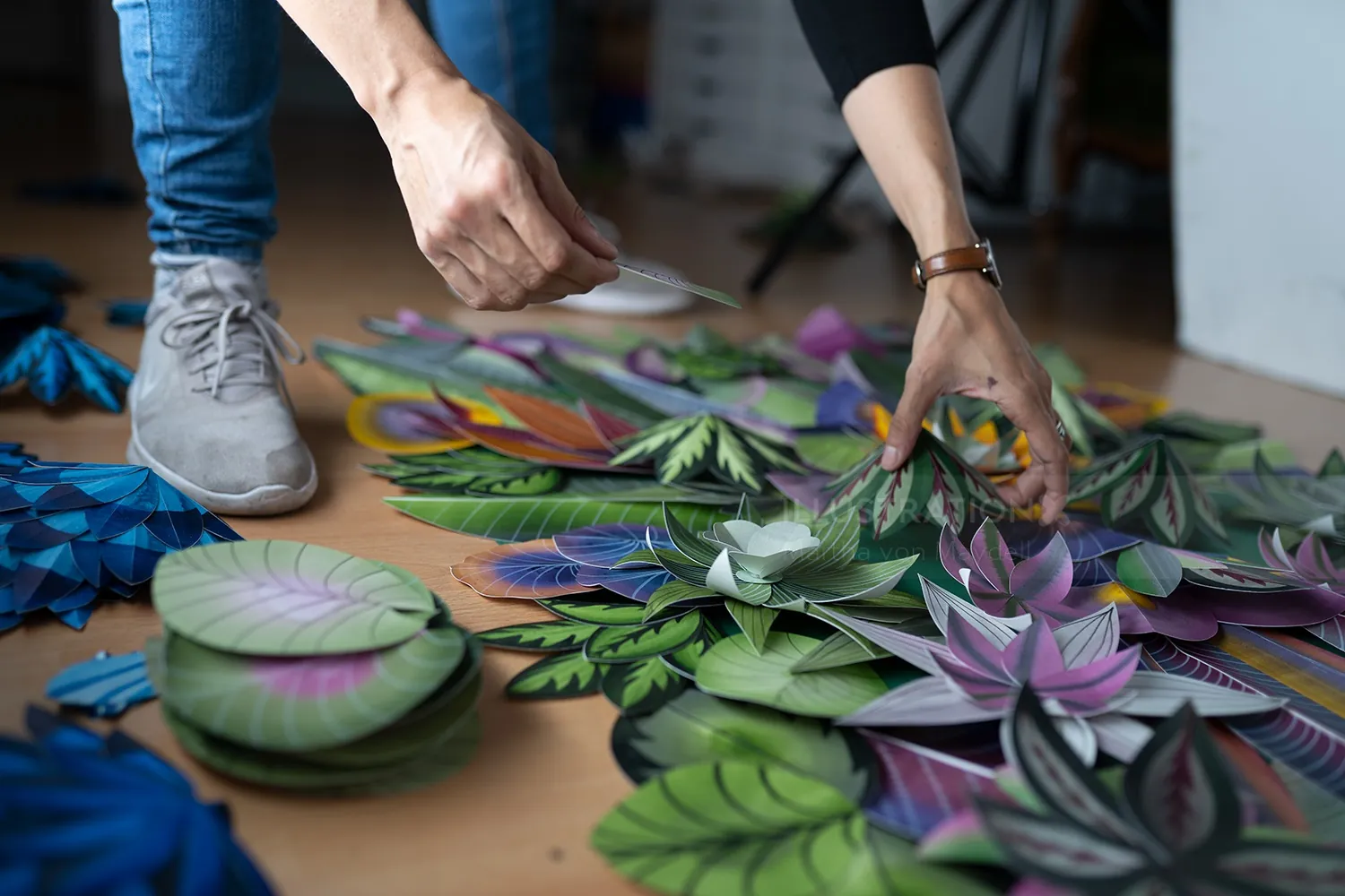 Hands arranging colorful paper leaves close up by artist Martha von Maydell