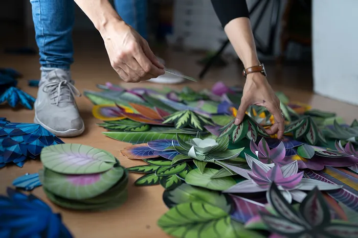 Hands arranging colorful paper leaves close up by artist Martha von Maydell