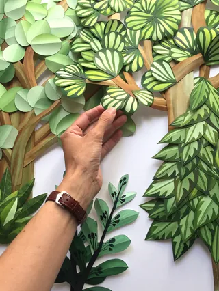 Hand arranging paper cutout leaves in various green patterns by Martha von Maydell