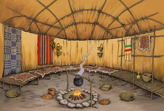 Interior of traditional round hut with fire and hanging textiles by Martin Hargreaves