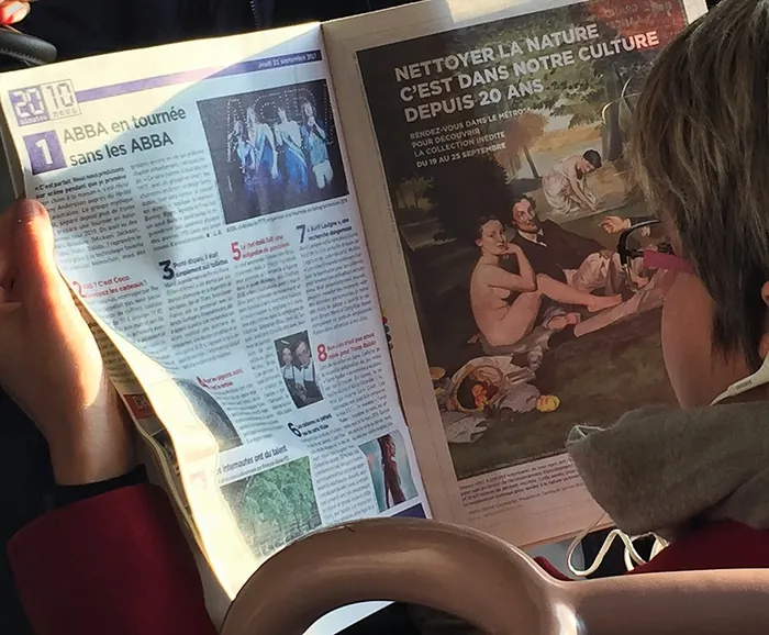 Person reading French magazine with ABBA and nature culture articles.