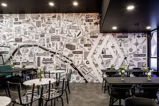 Cafe with black and white city map mural and black tables and chairs.