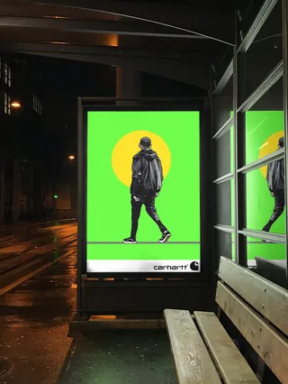 Person walking shown in bright bus stop advertisement at night