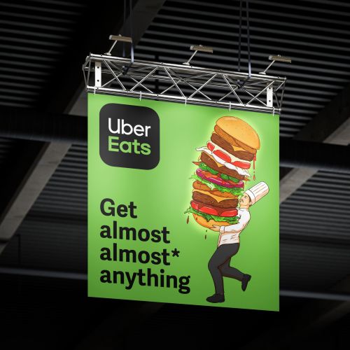 Uber Eats banner showing a person carrying a large burger advertisement by Max Erwin