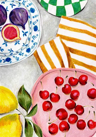 Red cherries on a pink plate with figs and lemons nearby