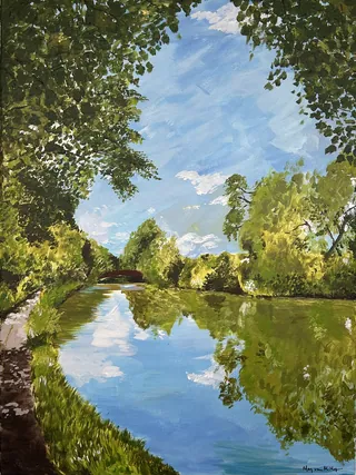 Calm river surrounded by green trees reflecting blue sky and clouds