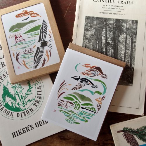Greeting cards and hiking guidebooks arranged on a wooden surface