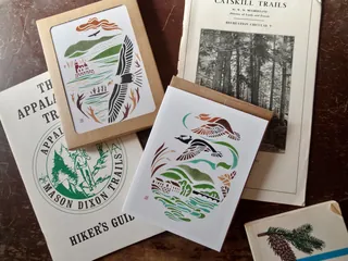 Greeting cards and hiking guidebooks arranged on a wooden surface