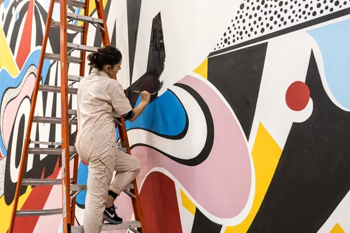 Artist Mel Cerri painting a colorful mural live at Keller Williams event