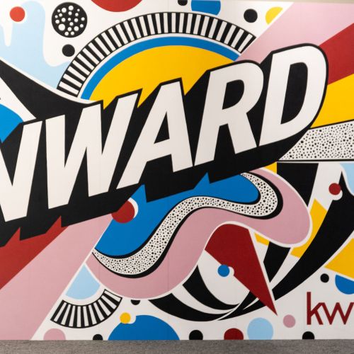 Man photographing colorful Onward mural by Mel Cerri