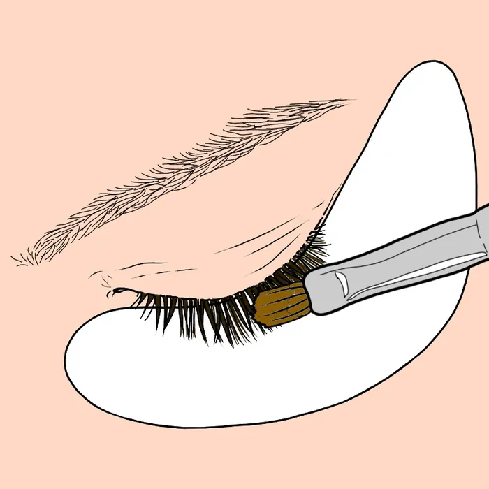 Makeup brush applying product to eyelashes with under-eye patch