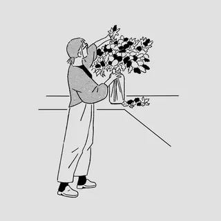 Person arranging flowers in a vase on a table
