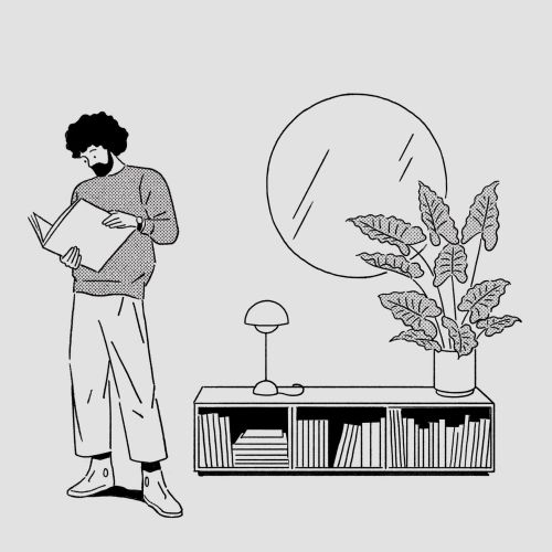 Man reading a book near bookshelf with plant and round mirror