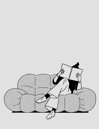 Individual sitting on sofa reading a book