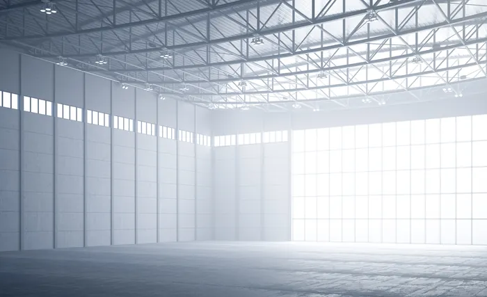 Bright, spacious empty industrial warehouse interior illuminated by natural light by Oliver Hassellu