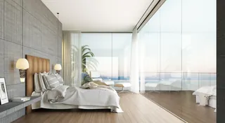 Bright modern bedroom with large glass windows overlooking the ocean