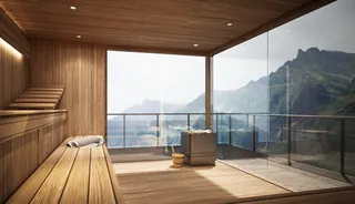 Wooden sauna interior with panoramic mountain view through glass wall