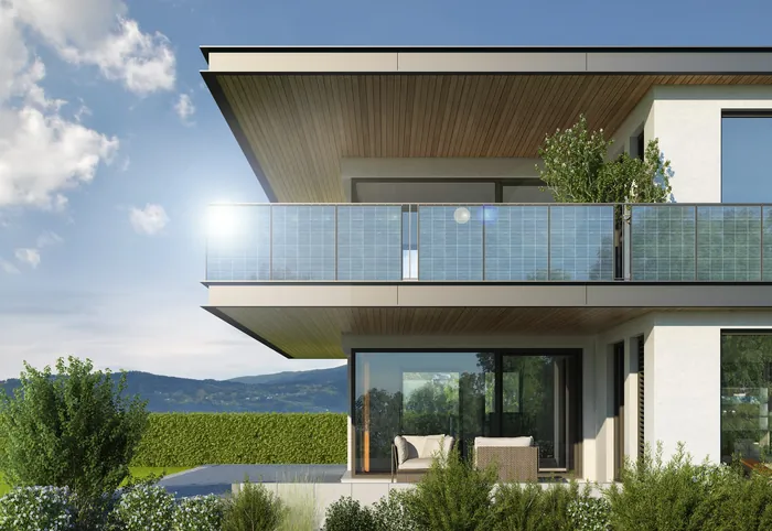 Modern house with balcony, glass railings, and garden outdoors