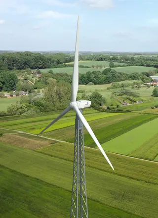 Wind turbine in green fields with blue sky background