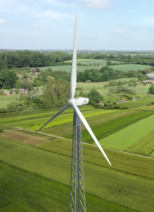Wind turbine in green fields with blue sky background