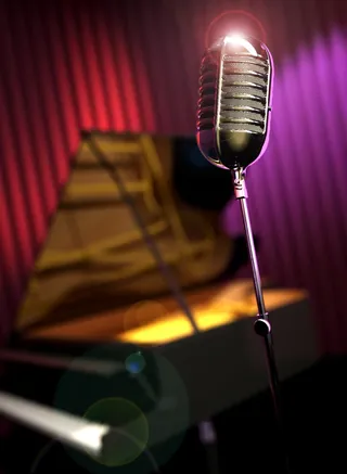 Vintage microphone and grand piano on stage with lighting by Oliver Hasselluhn