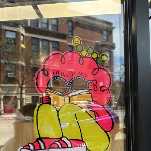 Cartoon character with red hair and sunglasses painted on window by Ollie Wootton