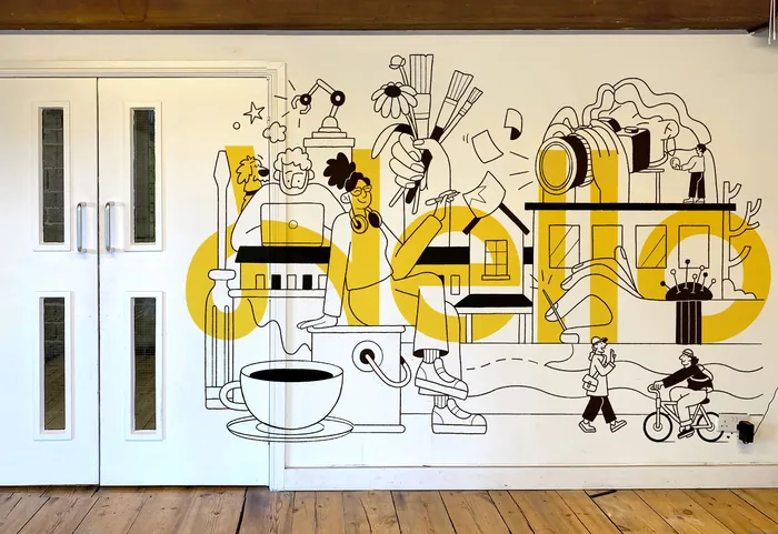 Black and white mural with yellow lettering depicting artist tools and figures