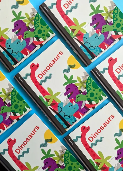 Notebooks with dinosaur illustrations and pens arranged in pattern