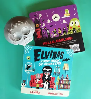 Elvira's book and Halloween skull decoration on green background