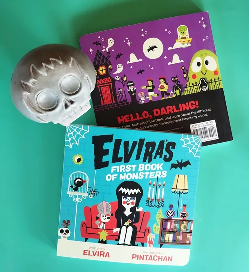 Elvira's book and Halloween skull decoration on green background