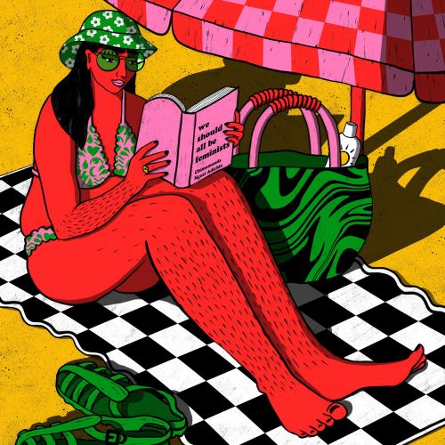 Woman reading book on beach towel under umbrella by Rachel Winter